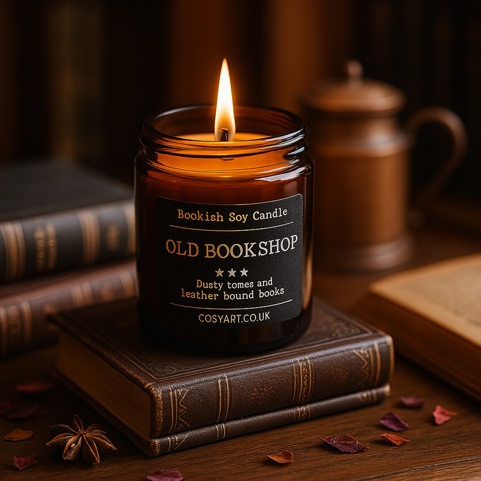 Old Bookshop candle by Cosy Art London styled on wood slice with glowing flame, surrounded by vintage books and warm autumn tones. Handmade in London.